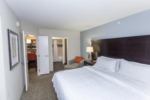 a hotel room with a large bed and a chair at Staybridge Suites Bowling Green by IHG in Bowling Green