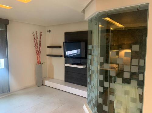 a living room with a tv and a glass wall at Motel Casablanca in Guadalajara