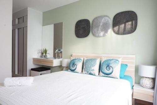a bedroom with a white bed with blue pillows at Beach Style Condo Pool, Gym, 1100m To Great Beach. in Nai Yang Beach