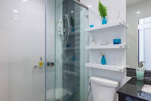 uma casa de banho com um WC e uma cabina de duche em vidro. em Beach Style Condo Pool, Gym, 1100m To Great Beach. em Nai Yang Beach