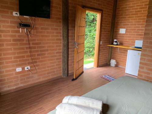 Una habitación con una cama y un televisor y una puerta. en Chalés Roma, en Santo Antônio do Pinhal