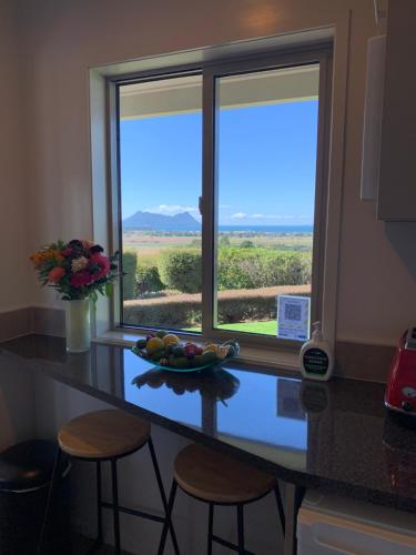 a kitchen counter with a bowl of fruit in front of a window at Views to unwind - self contained unit w/king bed in Ruakaka