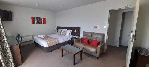 a hotel room with a bed and a chair at Dunedin Palms Motel in Dunedin