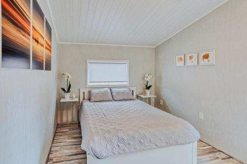 Modern & Cozy stand-alone apartment - perfect stay في Painted Post: غرفة نوم مع سرير وطاولتين مع ورد