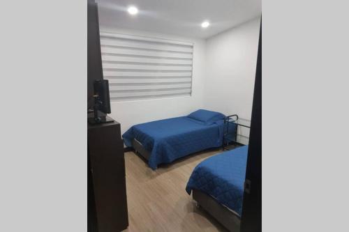 a bedroom with two beds and a television in it at Apartamento La Floresta con todas las comodidades in Bogotá