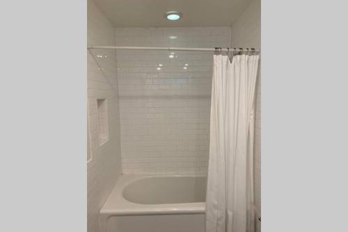 a bathroom with a tub and a white shower curtain at City Center Villa - Pool, Patio & Close To Beach! in Huntington Beach