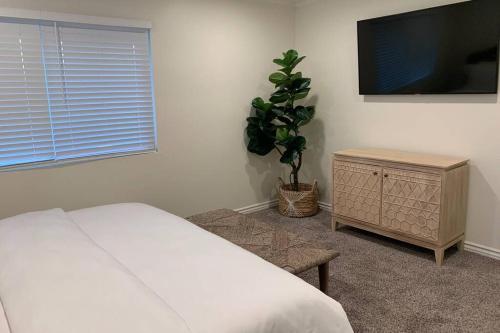 a bedroom with a bed and a tv and a plant at City Center Villa - Pool, Patio & Close To Beach! in Huntington Beach