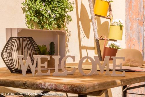 a welcome sign on a wooden table with plants at B&B Relais Druda in Cagli