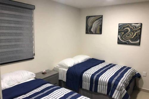 马萨特兰Departamento de lujo en el Malecón的有两张床和一扇窗户的卧室