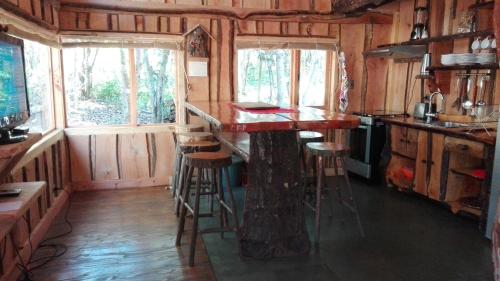 a kitchen with a bar in a tiny house at Wonderful rustic cabin, with native trees, with Rio Trancura, equipped in Pucón
