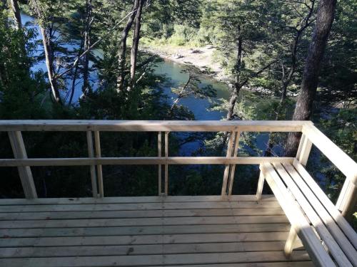 a wooden deck with a bench overlooking a river at Wonderful rustic cabin, with native trees, with Rio Trancura, equipped in Pucón