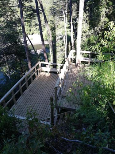 a wooden deck with a bench on a bridge at Wonderful rustic cabin, with native trees, with Rio Trancura, equipped in Pucón