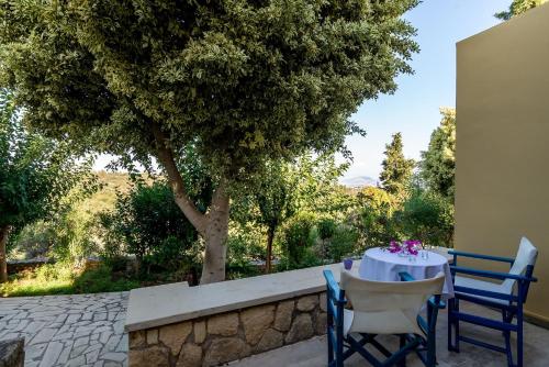 a table and chairs on a patio with a tree at Heliopetra studios, small village close to beaches in Koprána