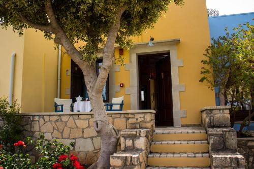 a yellow house with stairs and a tree at Heliopetra studios, small village close to beaches in Koprána