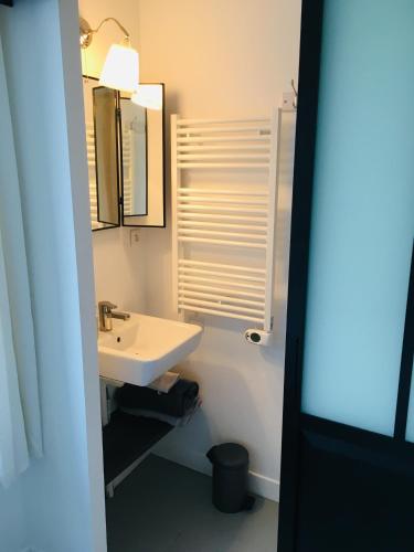 une salle de bain blanche avec un lavabo et un miroir dans l'établissement Les Hirondelles, à La Brée-les-Bains