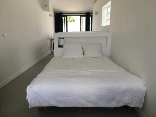 Cette petite chambre dispose d'un lit blanc et d'une fenêtre. dans l'établissement Les Hirondelles, à La Brée-les-Bains