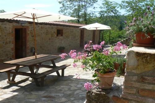 a picnic table with an umbrella and some flowers at Rustic Tuscan Apartment in Massa Marittima