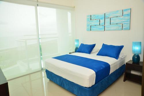 a bedroom with a large bed with blue pillows at MODERN 3 ALCOBAS APARTMENT in Cartagena de Indias