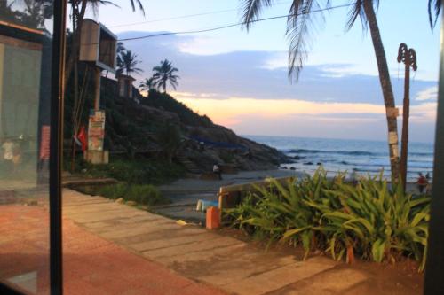 una playa con palmeras y el océano al atardecer en Stay Well Ayurvedic Beach Resort, en Kovalam