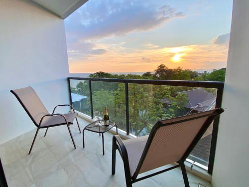 a balcony with two chairs and a table with a sunset at Escape Condominiums Beachfront Suites - Mae Phim in Rayong