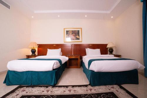 Habitación de hotel con 2 camas y alfombra en الجوهرة الأولى للوحدات السكنية - حي الحمدانية, en Yeda