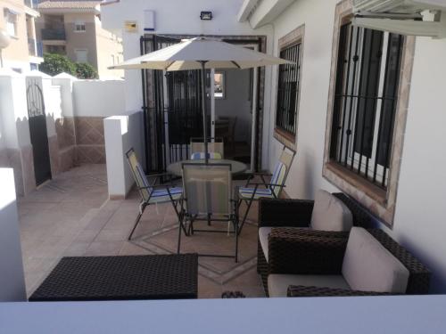 ロス・アルカサレスにある2 bedroom newly renovated bungalow close to bars & restaurantsのパティオ(テーブル、椅子、パラソル付)