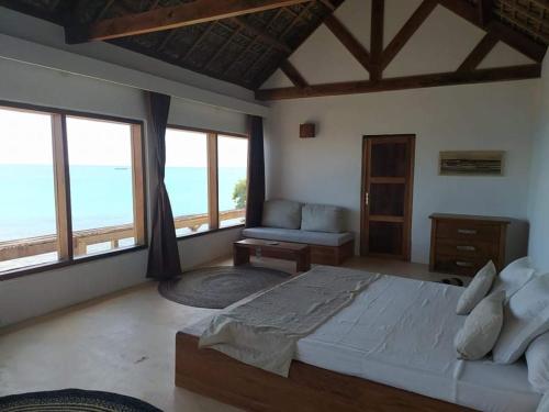 a bedroom with a large bed and large windows at Mazava Loha Resort in Diego Suarez