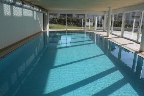 ルガノにあるIndoor Swimming Pool, Sauna, Fitness, Private Gardens, Spacious Modern Apartmentの青いタイルの床と窓が備わるスイミングプール