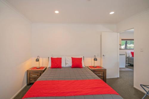 a bedroom with a red bed with two red pillows at Bayside Motel Whitianga in Whitianga