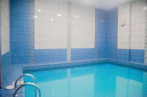 a bathroom with a swimming pool with blue tiles at Hotel Mir in Izhevsk