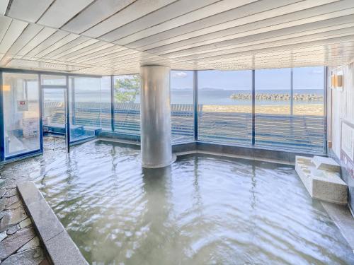 Yukai Resort Kaike Saichoraku في يوناغو: غرفة مع تجمع للمياه مع إطلالة على المحيط