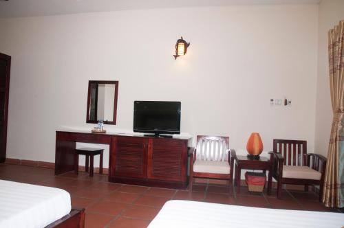 a bedroom with a tv and a desk with chairs at jardin des thes resort in Ấp Thiện Long