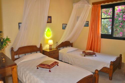a bedroom with two beds and two windows at Beachfront holiday house Eftichia in Agios Gordios