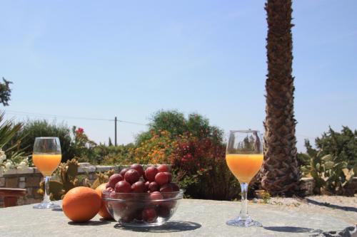 two glasses of wine and a bowl of fruit on a table at Cozy house close to the beach in Plaka