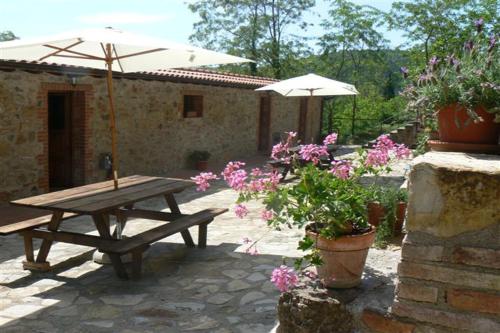 ein Picknicktisch mit Sonnenschirm und ein paar Blumen in der Unterkunft Rustic Tuscan style apartment in Massa Marittima