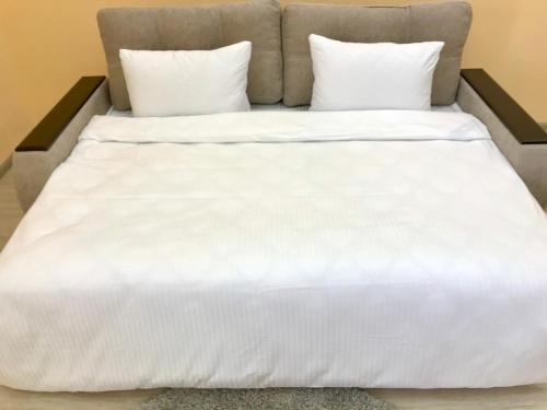 Cama blanca con sábanas y almohadas blancas en Абсолютно новая квартира-студия в ЖК Барский, en Khmelëva