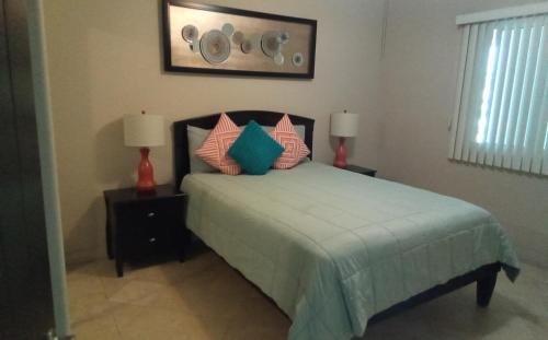 a bedroom with a bed with pillows and two lamps at Playa Bonita condo in Rosarito