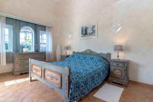 a bedroom with a bed with a blue comforter at Villa Oliveira Family villa BBQ Pool in Porches