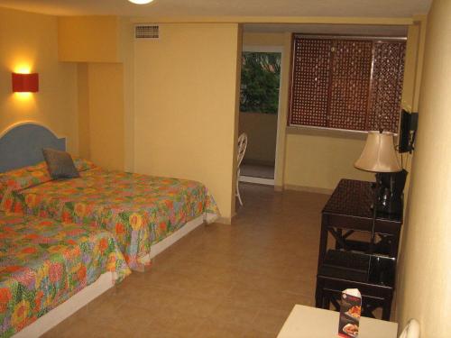 a hotel room with two beds and a window at Hotel Delfines Acapulco by NG Hoteles in Acapulco