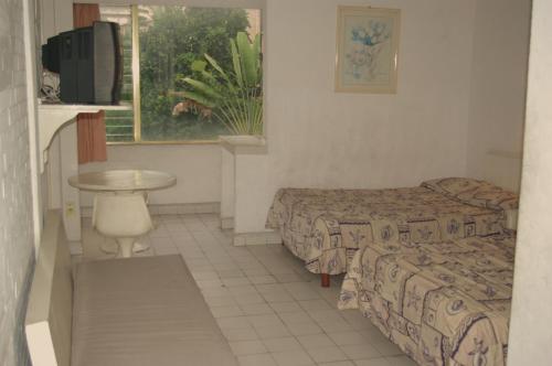a room with two beds and a table and a window at Hotel Delfines Acapulco by NG Hoteles in Acapulco