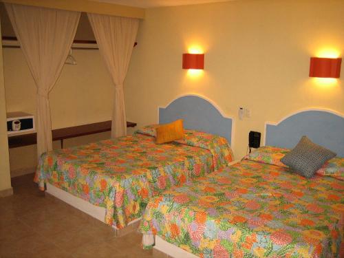 Hotel Delfines Acapulco by NG Hoteles في أكابولكو: غرفه فندقيه سريرين في غرفه