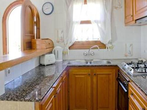 uma cozinha com armários de madeira, um lavatório e uma janela em Casa Louise - Great value 3 bedroom house in Son bou - Perfect for families em Son Bou