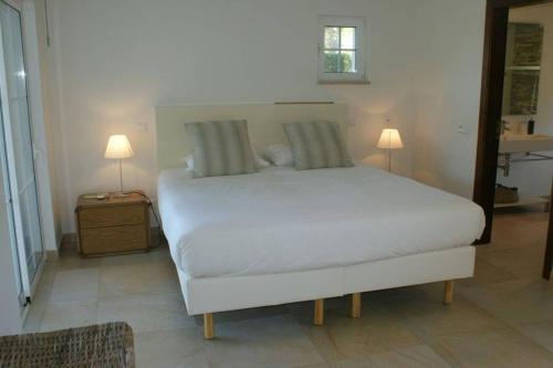 um quarto com uma cama branca e 2 candeeiros em Villa Sol Grande - Exclusive 5 Bedroom Villa - Great Pool Area - Perfect for Families em Quarteira