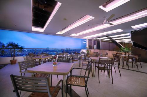 a restaurant with tables and chairs and a large screen at favehotel LTC Glodok in Jakarta
