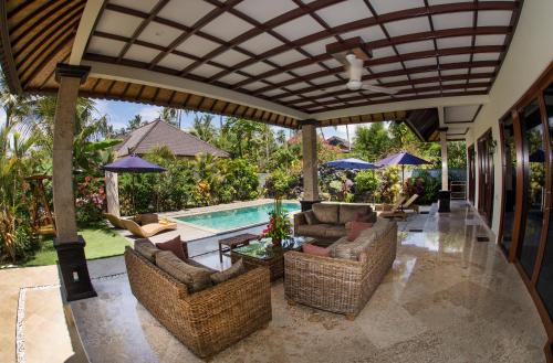 an outdoor patio with chairs and a swimming pool at Villa Barong in Candidasa