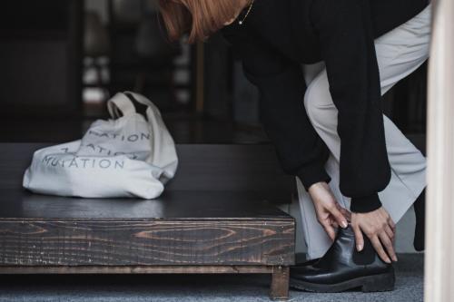 a woman tying her shoes on a trunk at Hostel Knot in Izu