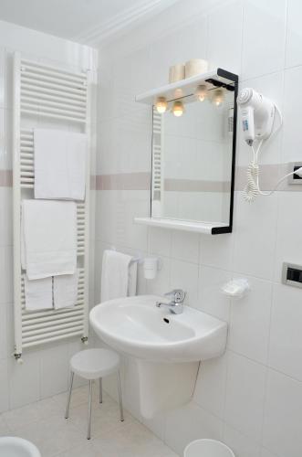 a white bathroom with a sink and a mirror at Residence Taufer in San Martino di Castrozza