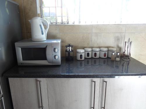 a kitchen counter with a microwave and cups on it at Waterglen Guest Lodge in Rustenburg