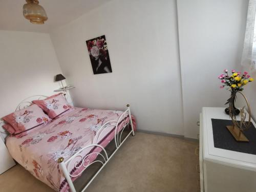 - une chambre avec un lit rose et un vase de fleurs dans l'établissement Appartement Vallée de Luchon, à Salles-et-Pratviel
