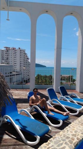 a man sitting on lounge chairs on a cruise ship at Hotel Delfines Acapulco by NG Hoteles in Acapulco